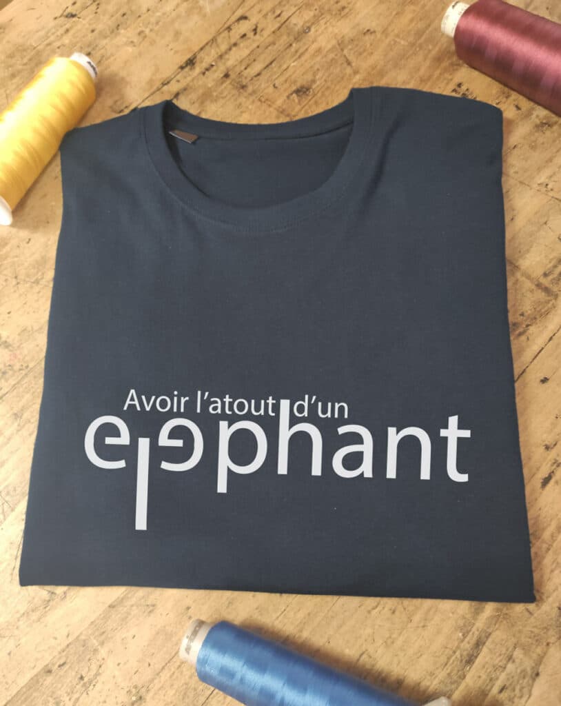 T-shirt bleu "Avoir l'atout d'un elephant" avec "ele" faisant une trompe et les oreilles d'un éléphant